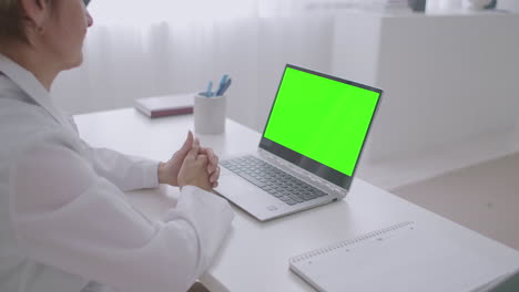 online-appointment-with-doctor-woman-physician-is-looking-at-green-display-of-laptop-for-chroma-key-technology-communicating-online-by-video-chat